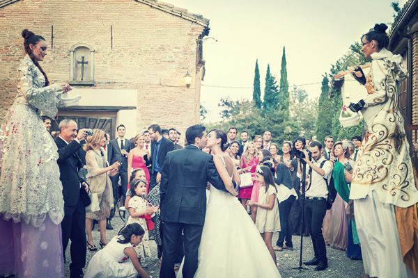 Novios entre dos zanquistas junto a los invitados